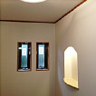 玄関ホール／設置した飾り棚と反射板付きの照明器具でお客様を暖かく迎えます。